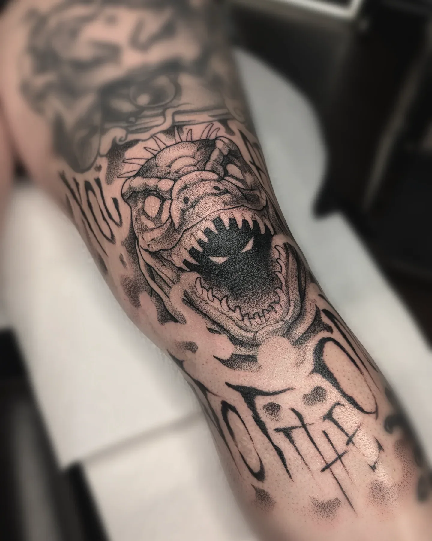 Black grey dinosaur skull lettering tattoo raleigh